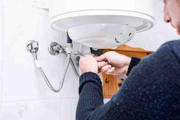 Plumber installs energy-efficient water heater designed for continuous use to reduce energy consumption and lower bills.